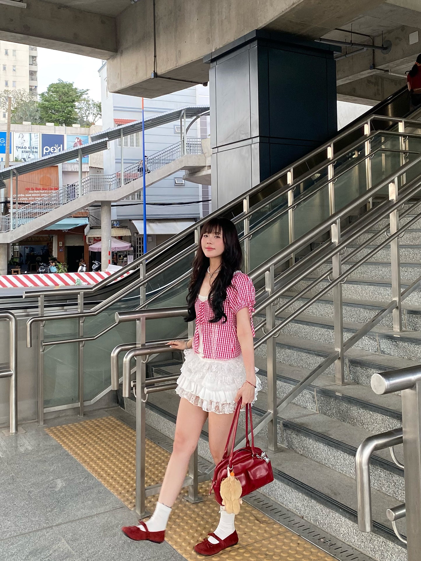 girl wearing cute gingham top posing while facing the side with one hand on the railing