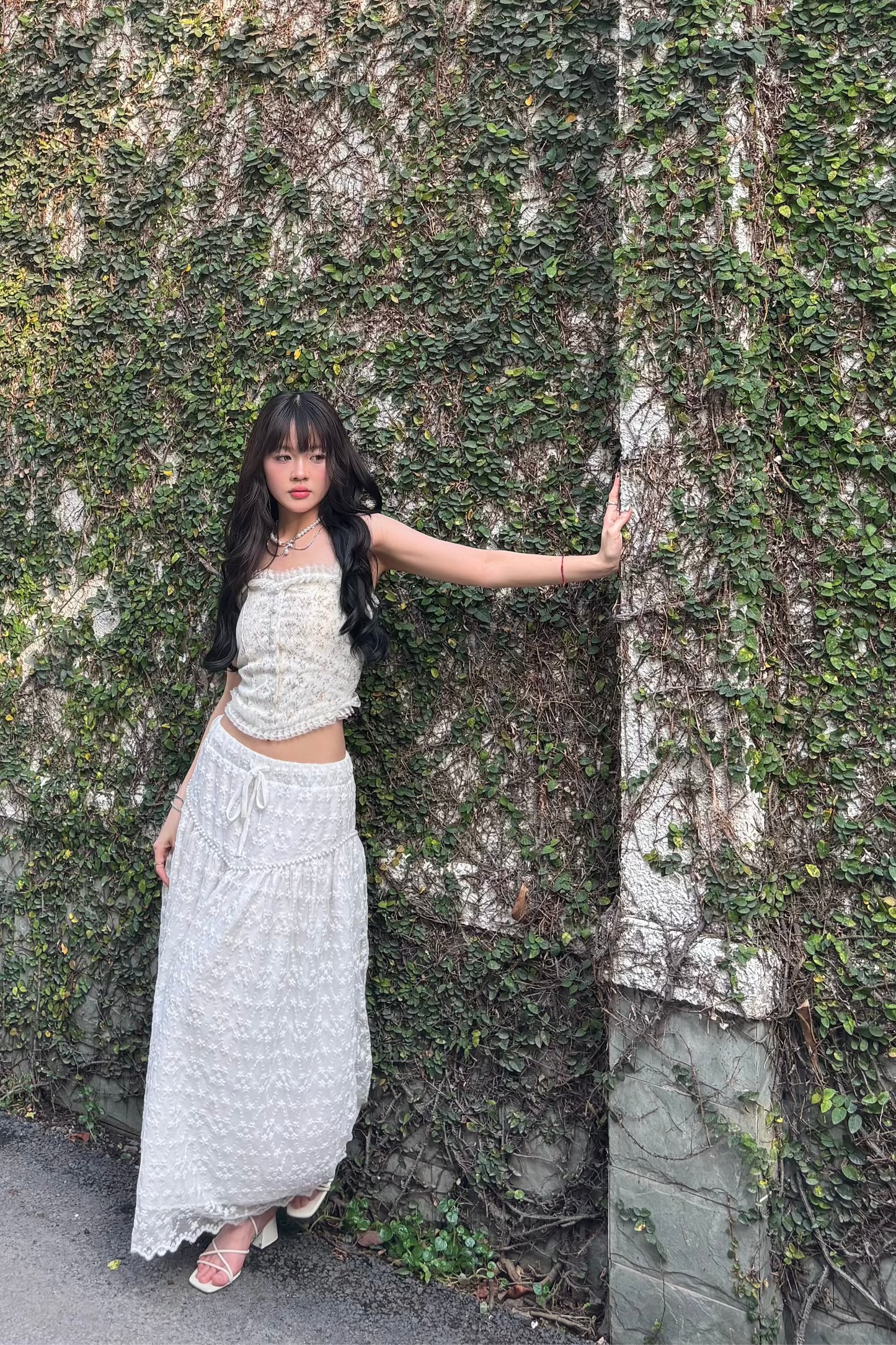 girl wearing white lace skirt posing with one arm on the wall